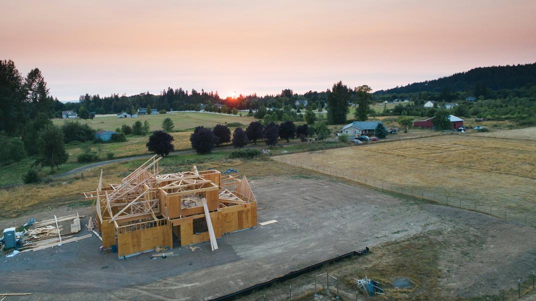 A new house frame going up on a gravel pad, seen from above.